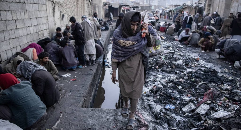 Afghan men consume drugs on a side street of a market in Afghanistan. Photo credit: Oliver Weiken/dpa